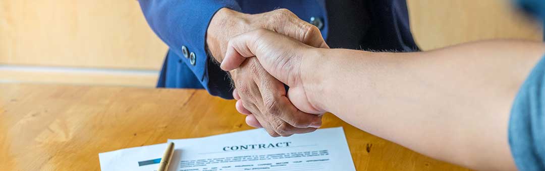 Shaking hands over an approved mortgage contract.