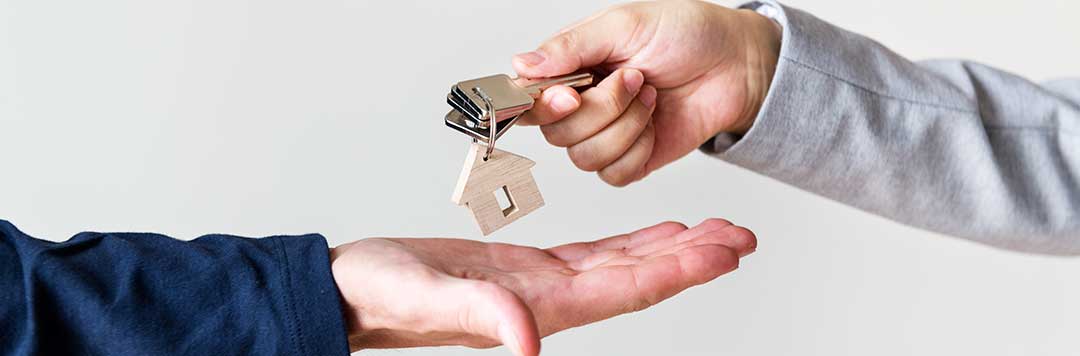 Two people exchanging housekeys to symbolize the transfer of ownership.
