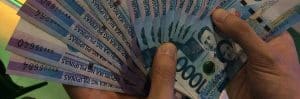 Thousand pesos bank notes held in two hands