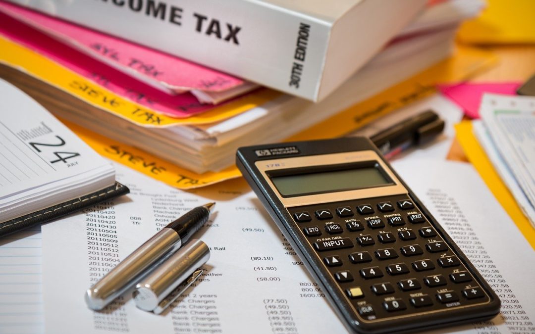 Calculator and pen on tax books and papers