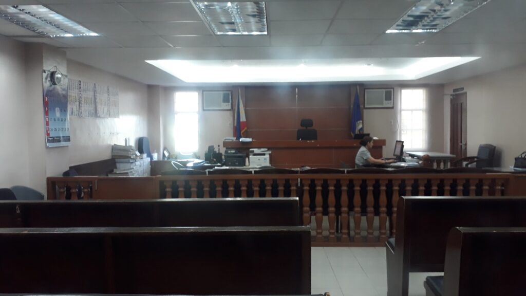 A photo of a typical Philippine court chamber where a Probate of Will would take place. There are a row of public benches, a wooden wall and the area where the lawyers and officials sit.