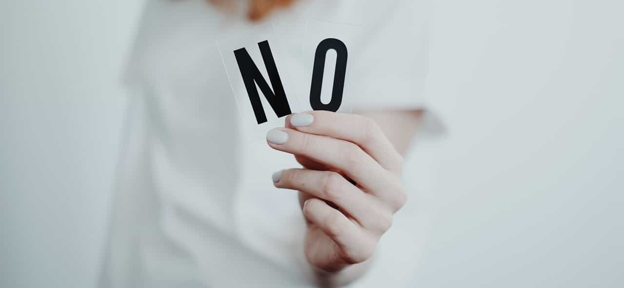 A hand holding a "No" sign