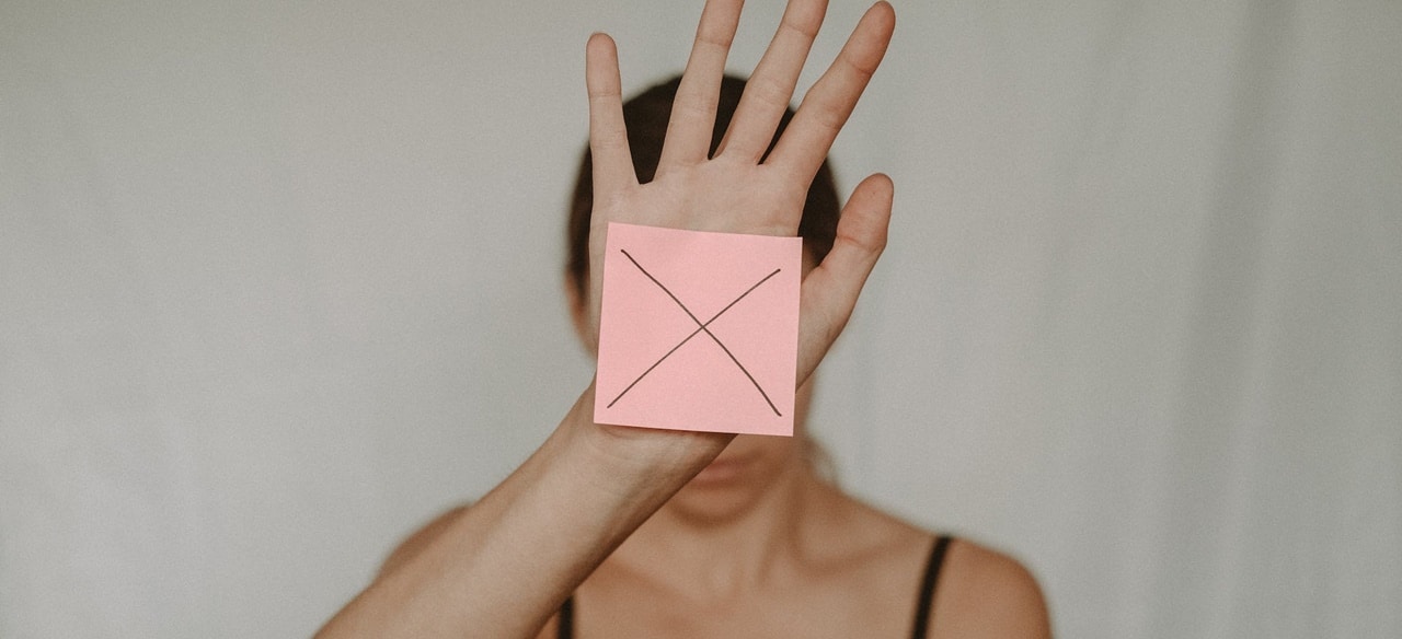 A woman with  a sticky post on her hand with an X