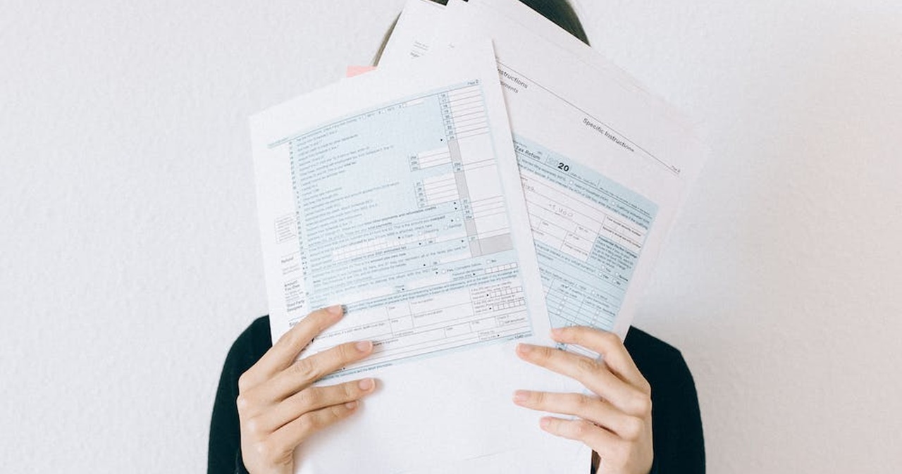 A woman covering her face with tax forms