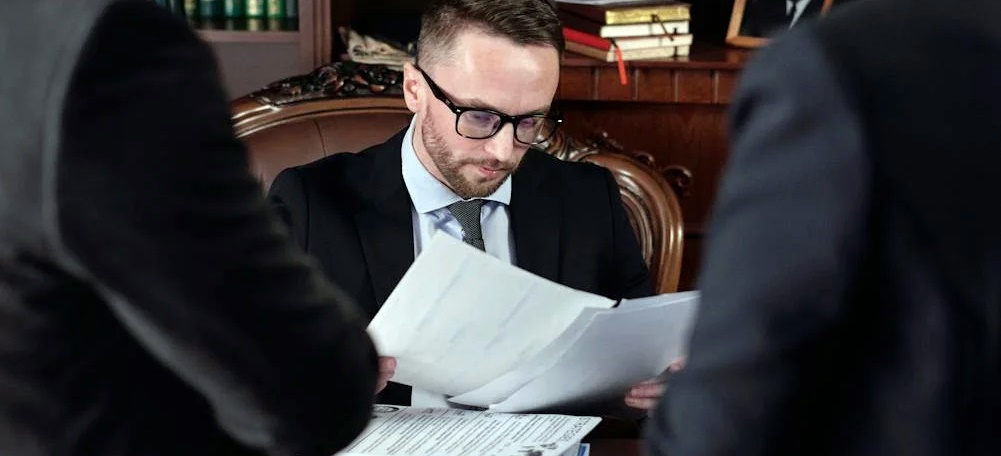 A man checking an invalid arbitration agreement in front of two people in formal attire