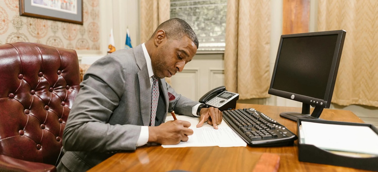 A man in his office writing on a piece of paper