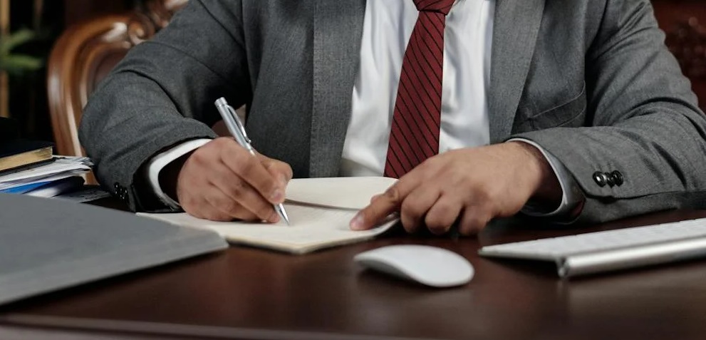 A man in formal attire signing a document