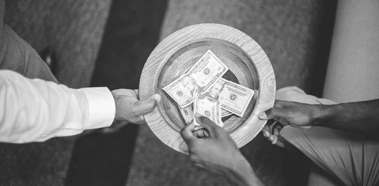 A person putting a dollar bill in the hat