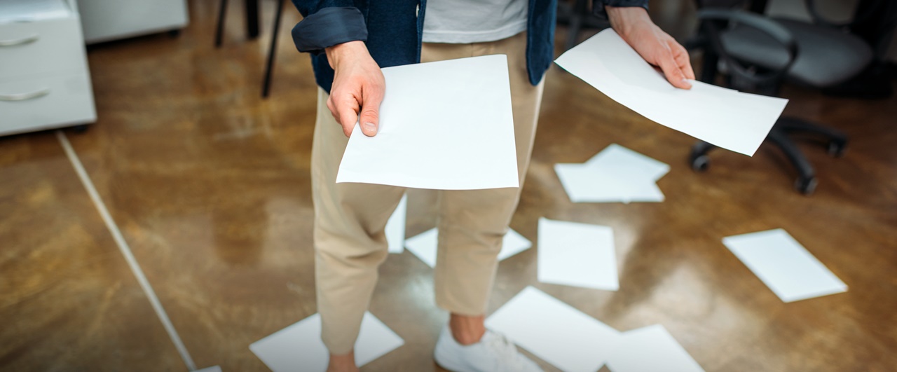 A man holding papers while the rest are on the floor