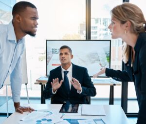 A man intervening between two people having a disagreement during a meeting