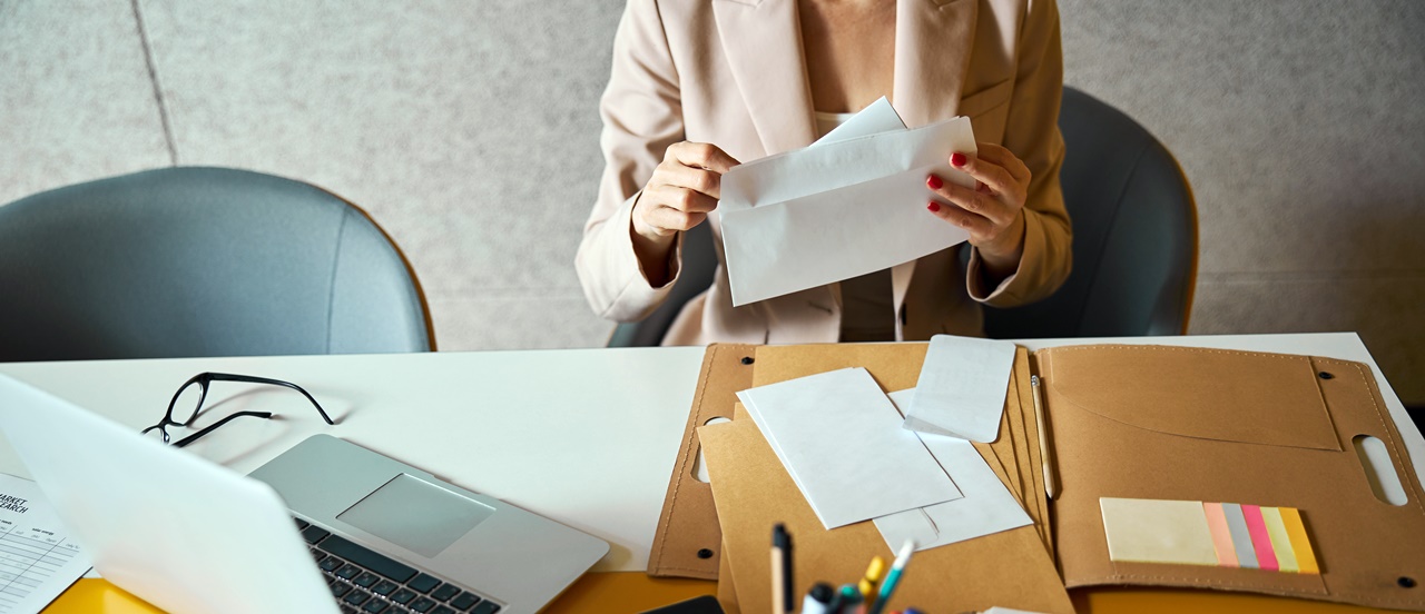 A woman opening a letter on her office desk