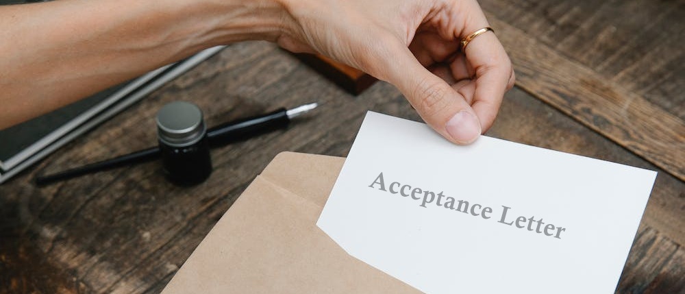 A person pulling an acceptance letter from an envelope