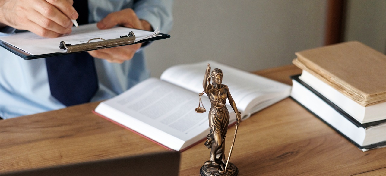 A man writing on a paper with the lady justice statue on his table