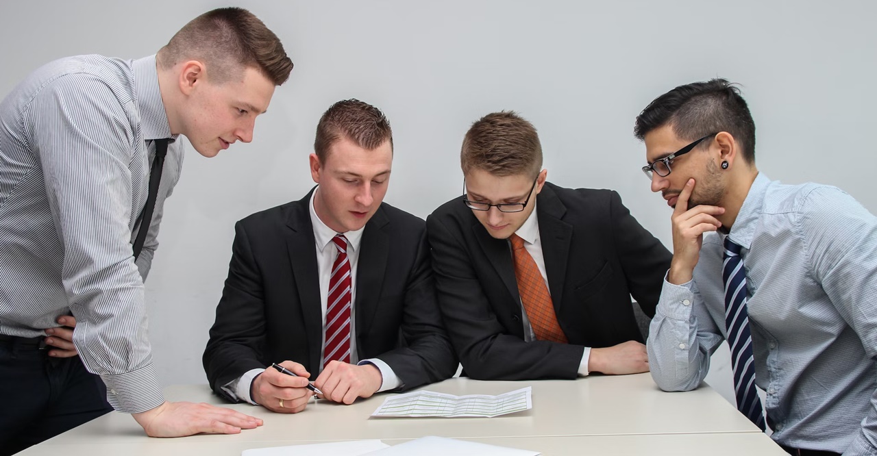 Four men looking at a piece of paper on a table