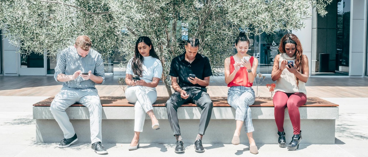 Young people on a beach looking at their cellphones symbolizing contacting our team of lawyers for registration assistance of a limited liability company